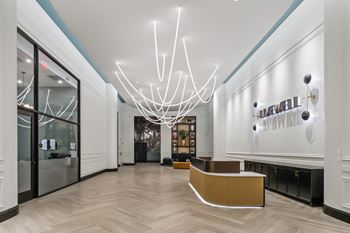 A reception area with a white reception desk and a large chandelier. at LiveWell Apartments, Pittsburgh
